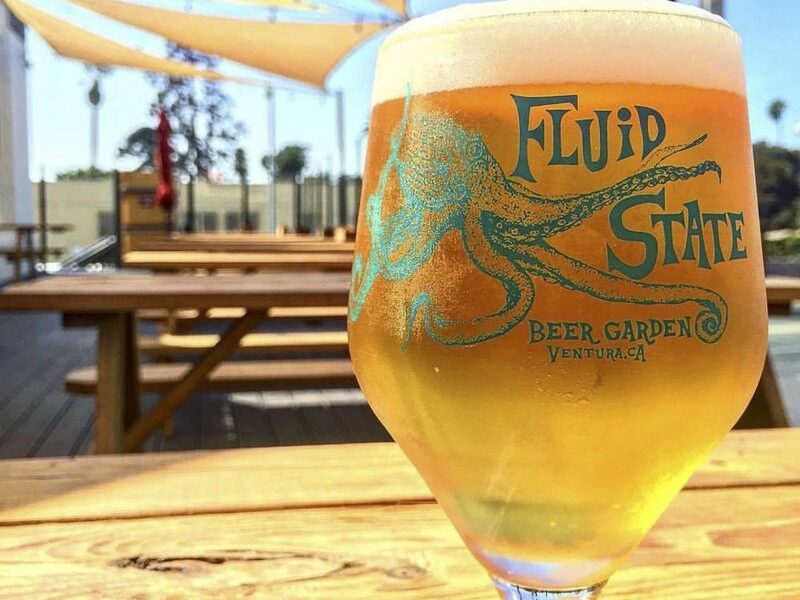A Fluid State Beer Garden glass of craft beer on a wooden patio table